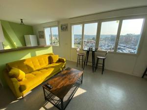 a living room with a yellow couch and a table at Superbe appartement avec vue panoramique sur Mers in Mers-les-Bains