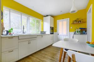 a kitchen with yellow walls and white cabinets and a table at Lewes Beautiful sunny flat in the historic town in Lewes