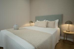 um quarto com uma grande cama branca e uma cabeceira azul em A Casa de Lena - Apartamentos Turísticos em Ribadumia