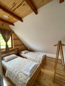 two beds in a room with wooden floors at Mokrogorski konaci in Mokra Gora