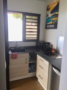 a kitchen with a counter and a sink and a window at Fare Anuanua in Haapiti