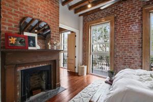 um quarto com uma lareira e uma parede de tijolos em Historic Garden District 5BR with Parking and Balcony em Nova Orleans