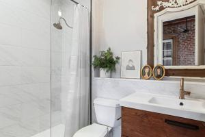 a bathroom with a toilet and a sink and a mirror at Historic Garden District 5BR with Parking and Balcony in New Orleans +6 photos