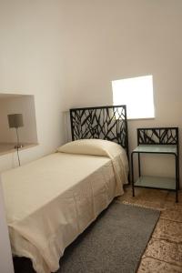 ein Schlafzimmer mit einem Bett, einer Lampe und einem Fenster in der Unterkunft Trullo Bianco in Putignano
