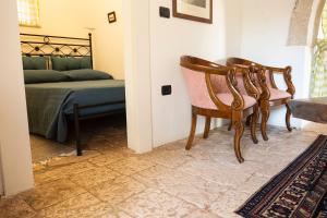 a bedroom with a bed and two chairs in a room at Trullo Bianco in Putignano