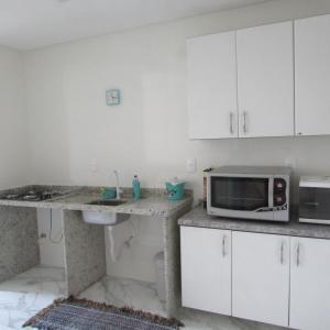 uma cozinha com um balcão com um micro-ondas e um lavatório em Apartamento em Balneario Camboriu em Balneário Camboriú