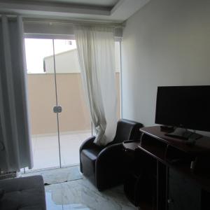uma sala de estar com um sofá e uma televisão e uma porta de vidro deslizante em Apartamento em Balneario Camboriu em Balneário Camboriú