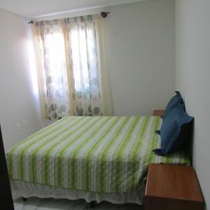 um quarto com uma cama com um cobertor verde e uma janela em Apartamento em Balneario Camboriu em Balneário Camboriú