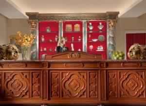 a woman standing behind a wooden dresser with a mirror at Bio Hotel Raphael - Relais & Châteaux in Rome