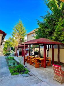 a pavilion with a table and benches in front of a building at Camere de inchiriat Sibel in Costinesti