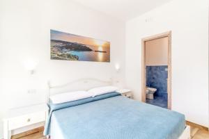 a white bedroom with a blue bed and a bathroom at Tramonto sul mare in Santa Teresa Gallura