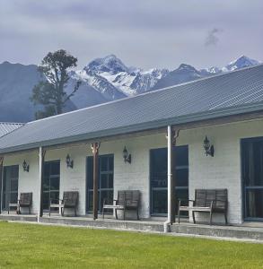 um edifício com bancos e montanhas cobertas de neve ao fundo em Mt Cook View Motel em Fox Glacier