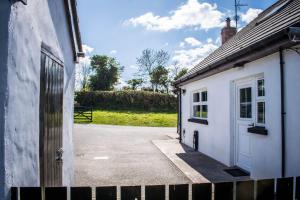 a white building with a door and a driveway at The Heights & Hollows Farmhouse, Saul, Downpatrick, SLEEPS 14 in Downpatrick