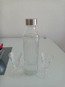 una botella de cristal y dos vasos en una mesa en Apartmani Bosco, en Tivat