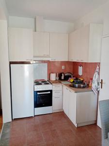 cocina con armarios blancos y nevera blanca en Apartmani Bosco en Tivat