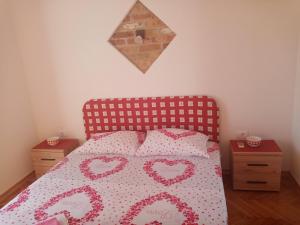 Un dormitorio con una colcha con corazones. en Apartmani Bosco, en Tivat