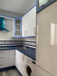 cocina con armarios blancos y lavadora en Apartamento turístico La Joya, en Huelva