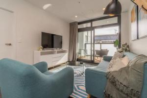 a living room with two blue chairs and a television at City Pulse Apartment with car park and city views in Auckland