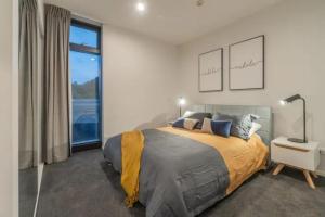 a bedroom with a bed and a large window at City Pulse Apartment with car park and city views in Auckland