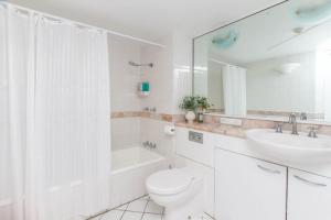 a white bathroom with a toilet and a sink at Inner City One Bedroom Apartment with Pool View 22 in Cairns