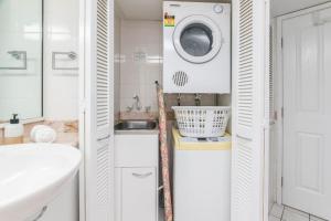 a bathroom with a sink and a washing machine at Inner City One Bedroom Apartment with Pool View 22 in Cairns