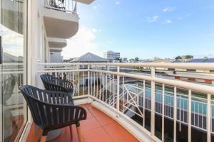 een balkon met 2 stoelen en een zwembad bij Inner City One Bedroom Apartment with Pool View 22 in Cairns