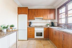 una cucina con armadi in legno e frigorifero bianco di Sweet Celia a Playa Blanca