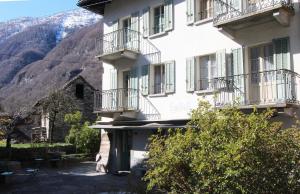 a white building with balconies and a mountain at Casa Eva in Brione