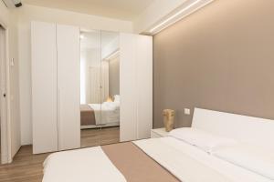 1 dormitorio con 2 camas blancas y espejo en Appartamento L'Essenziale, en Vieste