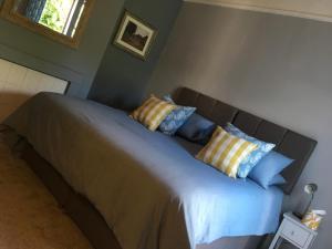 um quarto com uma cama com almofadas azuis e amarelas em The One @ West End em West Haddon