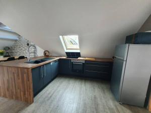 uma cozinha com armários azuis e um frigorífico branco em Charmant appartement proche commerces et plages em Le Guilvinec