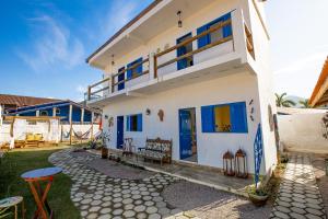 Cette maison blanche dispose de fenêtres bleues et d'une terrasse. dans l'établissement QUINTAL DO SON CHALÉS, à Ubatuba