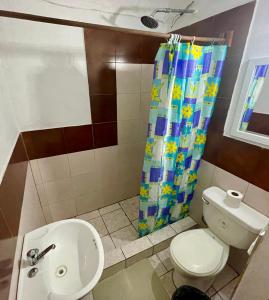 a bathroom with a toilet and a shower curtain at Hostal Inn 1 in Flores