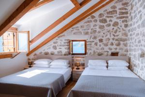 - 2 lits dans une chambre avec un mur en pierre dans l'établissement GuestHouse Mrshe Palace, à Perast