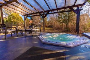 a hot tub on a patio under a pergola at Vadgalamb Apartman & Jacuzzi in Miskolctapolca