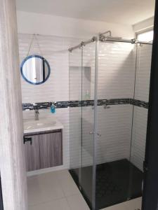 La salle de bains est pourvue d'une douche en verre et d'un lavabo. dans l'établissement Apartamento de lujo , con linda vista, cuarto piso, à Cartago