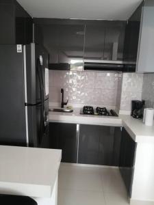 a kitchen with a black refrigerator and white counter top at Apartamento de lujo , con linda vista, cuarto piso in Cartago