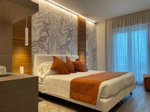 ein Schlafzimmer mit einem großen Bett mit orangefarbenen Kissen in der Unterkunft Hotel Aurora in Lido di Jesolo