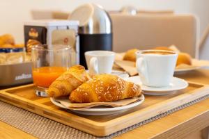 ein Tablett mit einem Teller Croissants und Tassen Kaffee in der Unterkunft Balneum Rooms & SPA in Mirabella Eclano