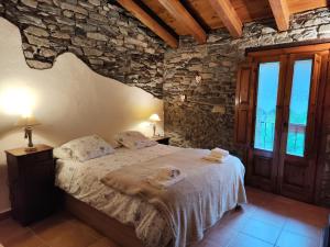 1 dormitorio con cama y pared de piedra en Allotjaments Cal Llarg en Molló