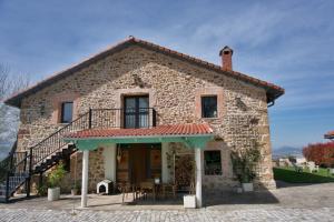 an old stone house with a balcony and tables at FINCA ALEGRANZA in Torrelavega