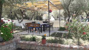 een terras met een tafel en stoelen onder een luifel bij Vila Juna in Ksamil