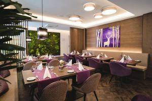 バーデン・バーデンにあるホテル メルクール - スーペリアの紫のテーブルと椅子が並ぶレストラン
