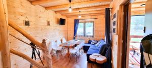 eine Blockhütte mit einem Tisch, Stühlen und einem Sofa in der Unterkunft Domki Na Szlaku Bieszczady in Uherce Mineralne