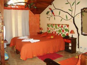 a bedroom with a red bed with a tree on the wall at Peruíbe Suíte Flat Hotel in Peruíbe