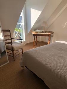 een slaapkamer met een bed, een bureau en een stoel bij Camélia rouge in Granville