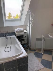 baño con bañera, lavabo y ventana en Camélia rouge en Granville