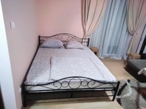Schlafzimmer mit einem schwarzen Bett mit weißer Bettwäsche und Kissen in der Unterkunft Apartman 1 in Vrnjačka Banja
