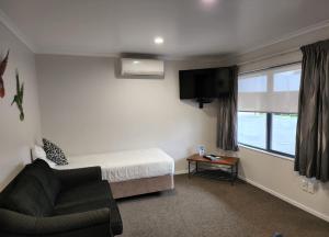 a bedroom with a bed and a chair and a window at ASURE Albert Park Motor Lodge in Te Awamutu