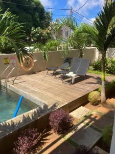 two chairs on a wooden deck next to a swimming pool at Modern and cosy condo: Westwood Apartments in Flic-en-Flac